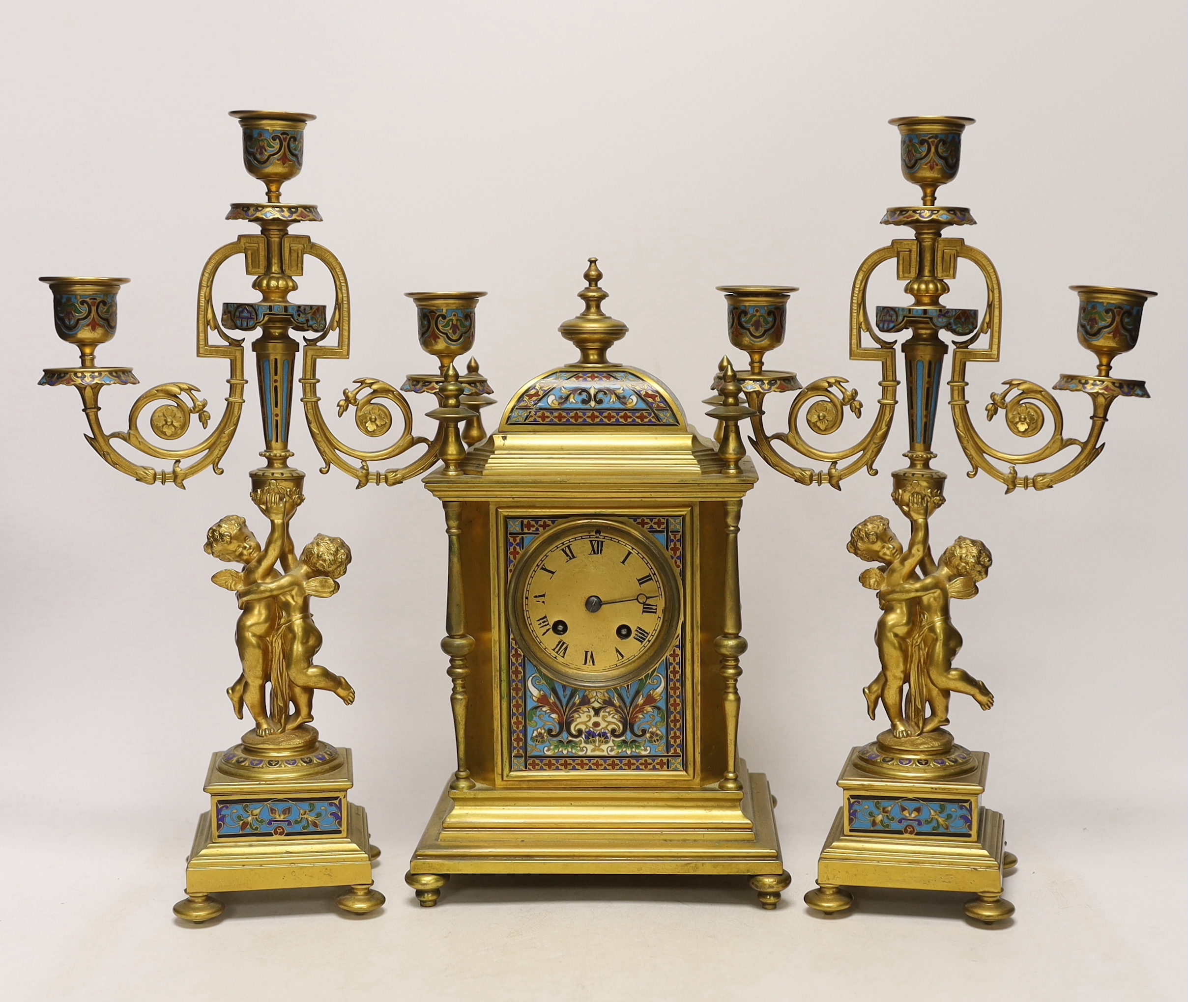 A late 19th/early 20th century French champleve and gilt metal clock garniture, 37cm